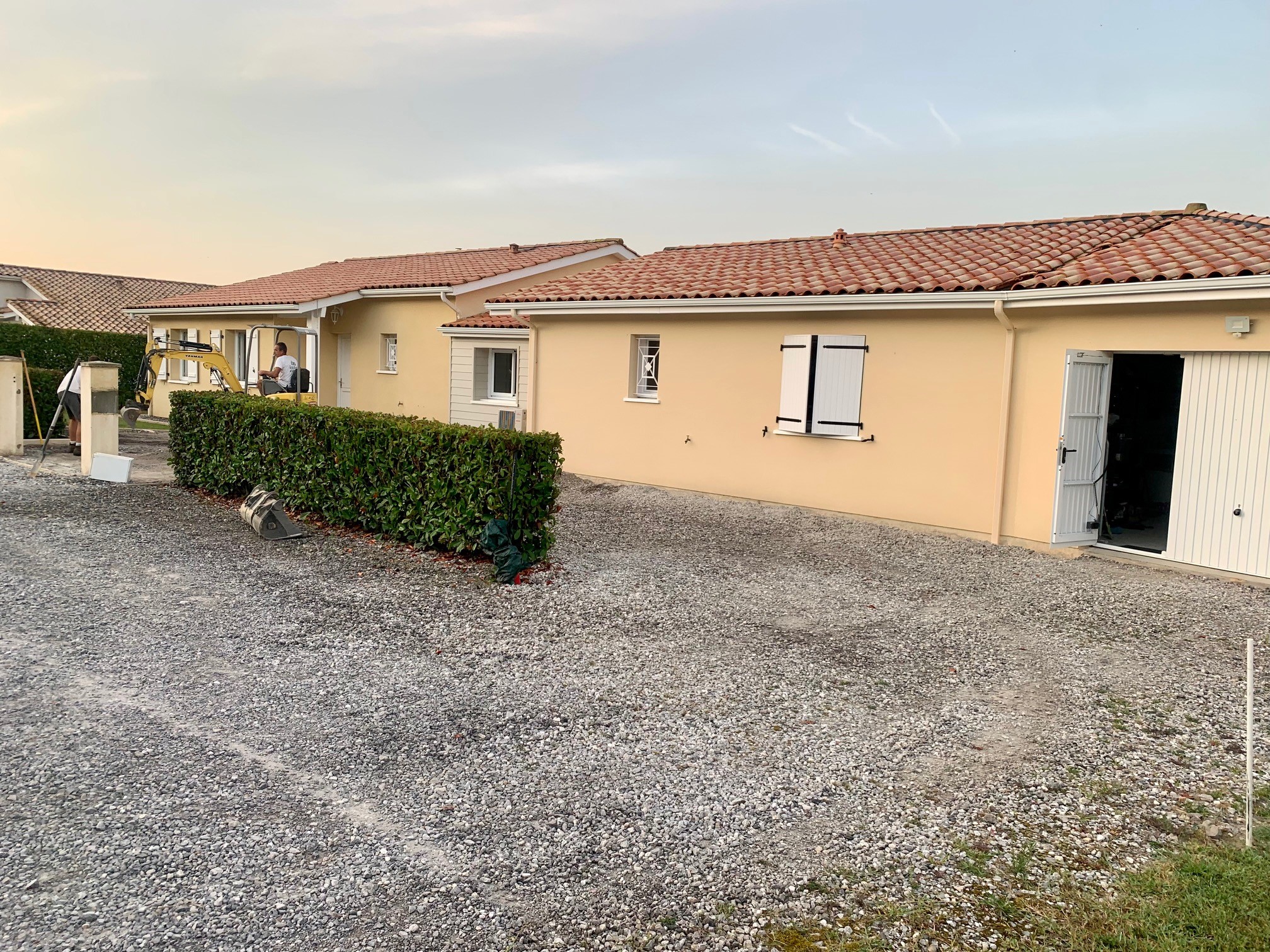 Homme relaxé près d'un olivier bonsaï dans son jardin Un homme souriant en t-shirt vert et short beige assis à côté d'un olivier bonsaï dans un jardin aménagé.